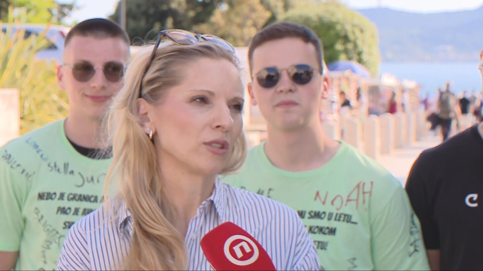 Учительница Нина Лучич даёт интервью Nova TV в Задаре, за ней выпускники в зелёных футболках