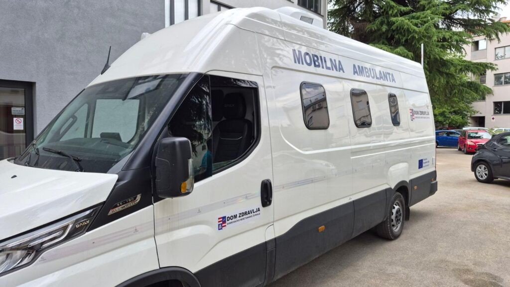 Боковой вид нового мобильного медпункта IVECO Daily с надписью MOBILNA AMBULANTA, припаркованного у медучреждения
