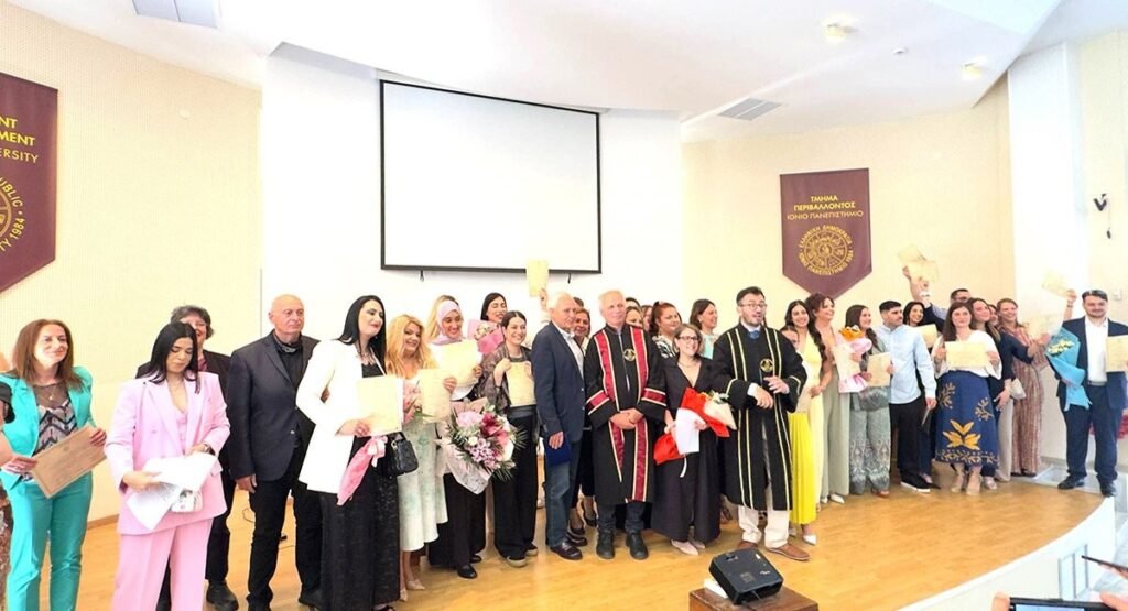 Выпускники Ионического университета и преподаватели в академических мантиях позируют с дипломами в амфитеатре кампуса на Закинфе