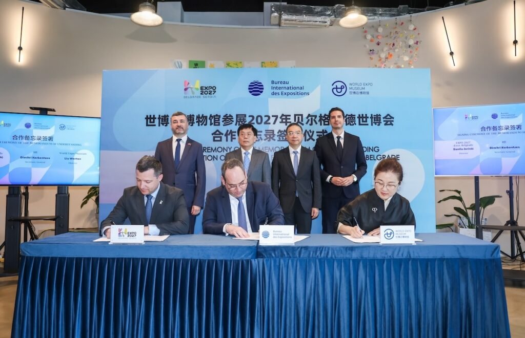 Церемония подписания Меморандума о взаимопонимании между BIE, EXPO 2027 и Музеем Всемирной выставки в Шанхае: три представителя сторон скрепляют документы за общим столом на фоне логотипов организаций
