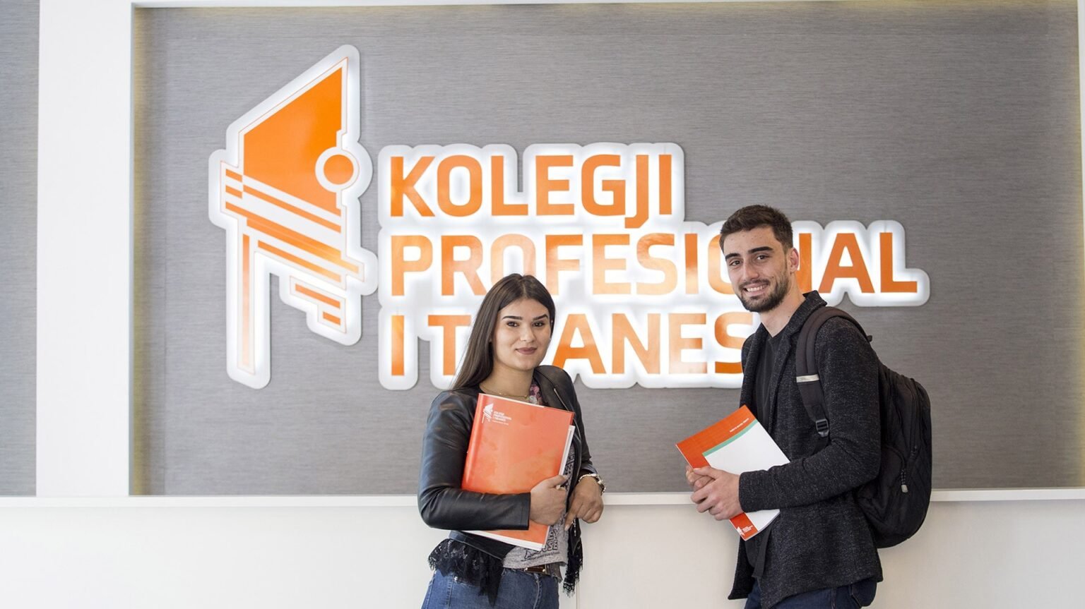 Студенты Tirana College of Technology у фирменной стены с логотипом колледжа в Тиране — учебное заведение, организовавшее конкурс TCT Energy Challenge 2026