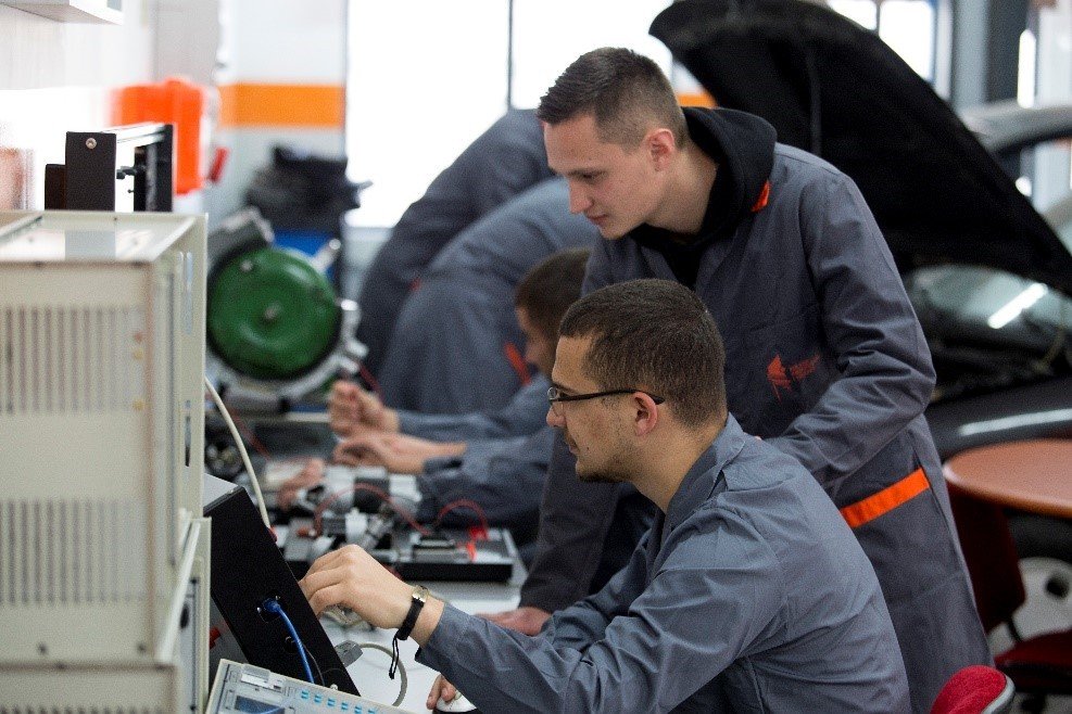 Студенты Tirana College of Technology работают с электронным стендом и автомобильным двигателем в инженерной лаборатории колледжа
