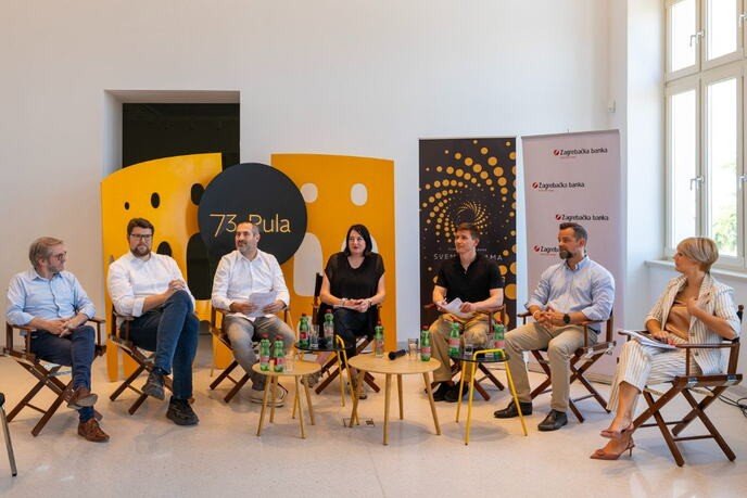 Презентация программы 73-го Пульского кинофестиваля в Археологическом музее Истрии: участники пресс-конференции на сцене с фестивальной табличкой «73. Pula» и партнёрскими постерами