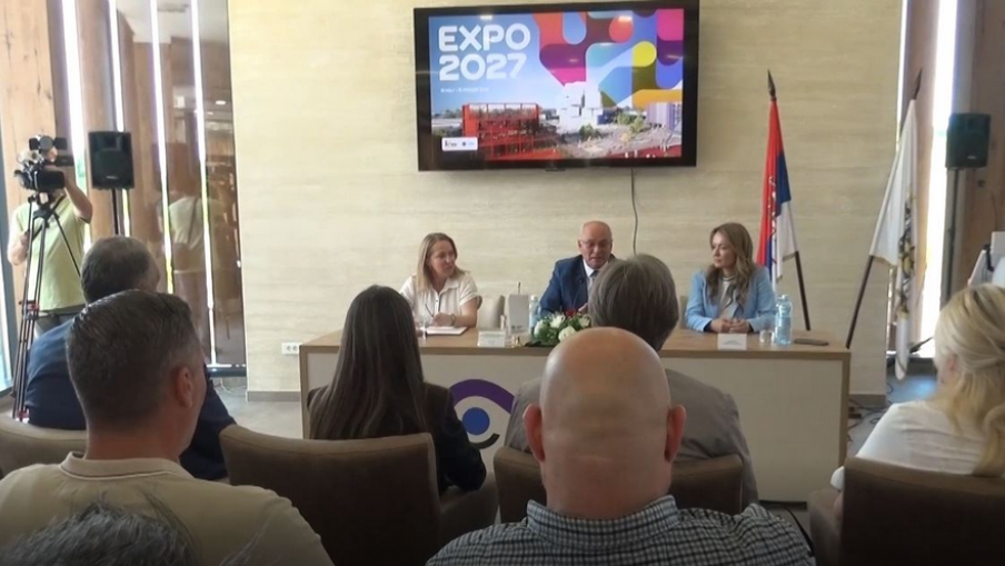 Царичин Град едет на EXPO 2027: презентация выставки Министр Маја Гойкович и министр Тања Пауновић открывают презентацию выставки EXPO 2027 на археологическом памятнике Царичин град у Лебане — большой экран с логотипом EXPO и сербским флагом на заднем плане