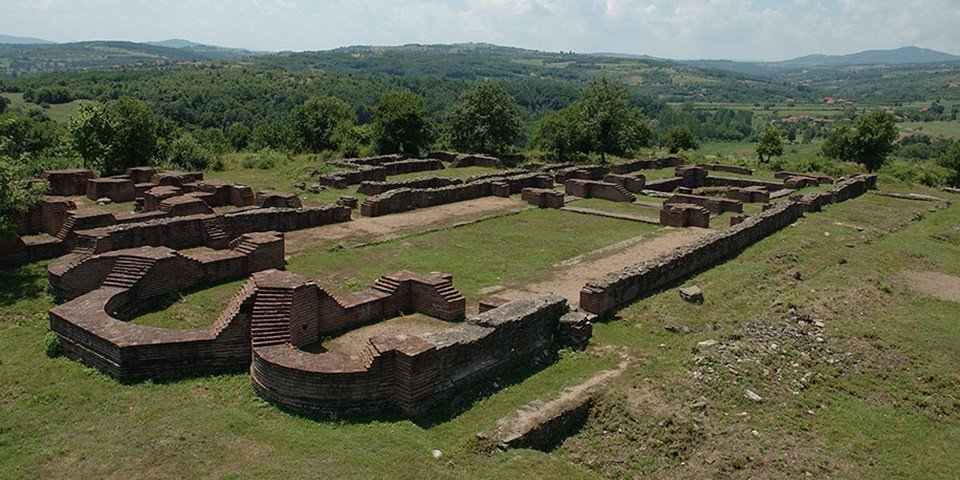 Панорама раскопанных краснокирпичных стен раннeвизантийского города Царичин град на фоне зелёных холмов южной Сербии — основная часть археологического памятника Юстиниана Прима