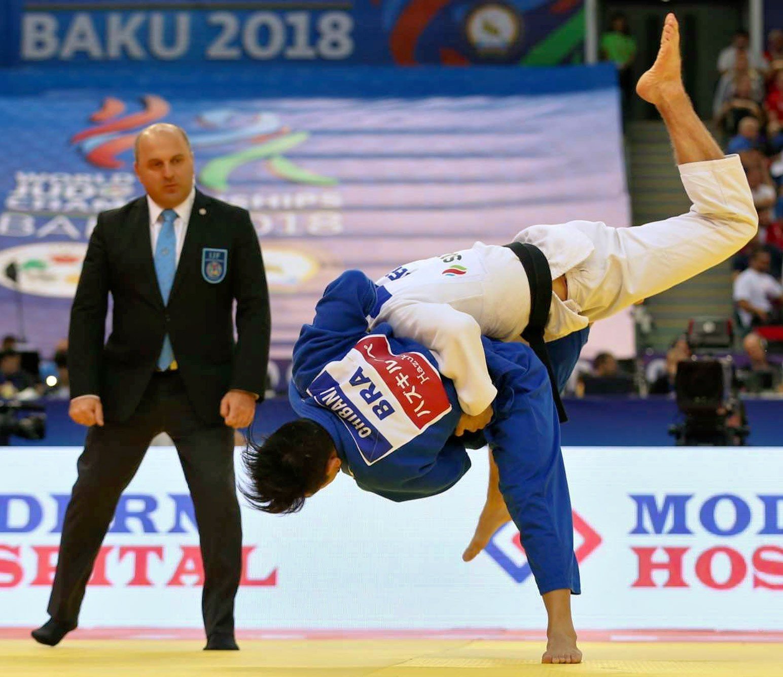 Архивный кадр из чемпионата мира в Баку 2018 года: судья наблюдает за броском, на фоне баннер «BAKU 2018» — азербайджанская столица уже принимала турнир такого уровня